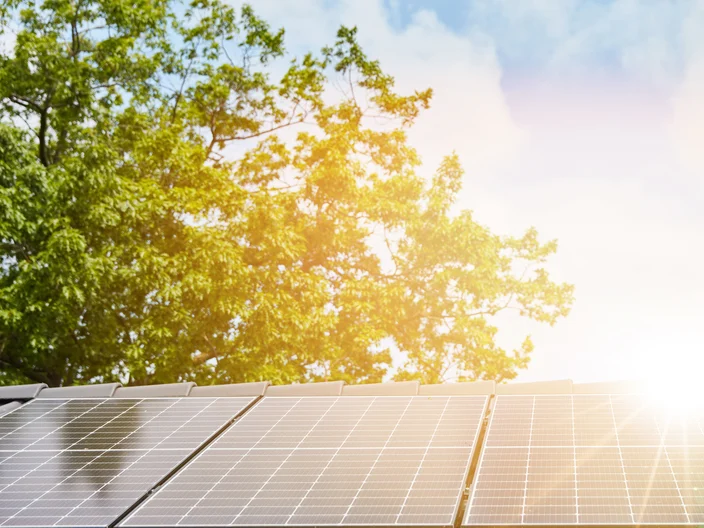 Sun shines over roof with solar panels for renewable energy